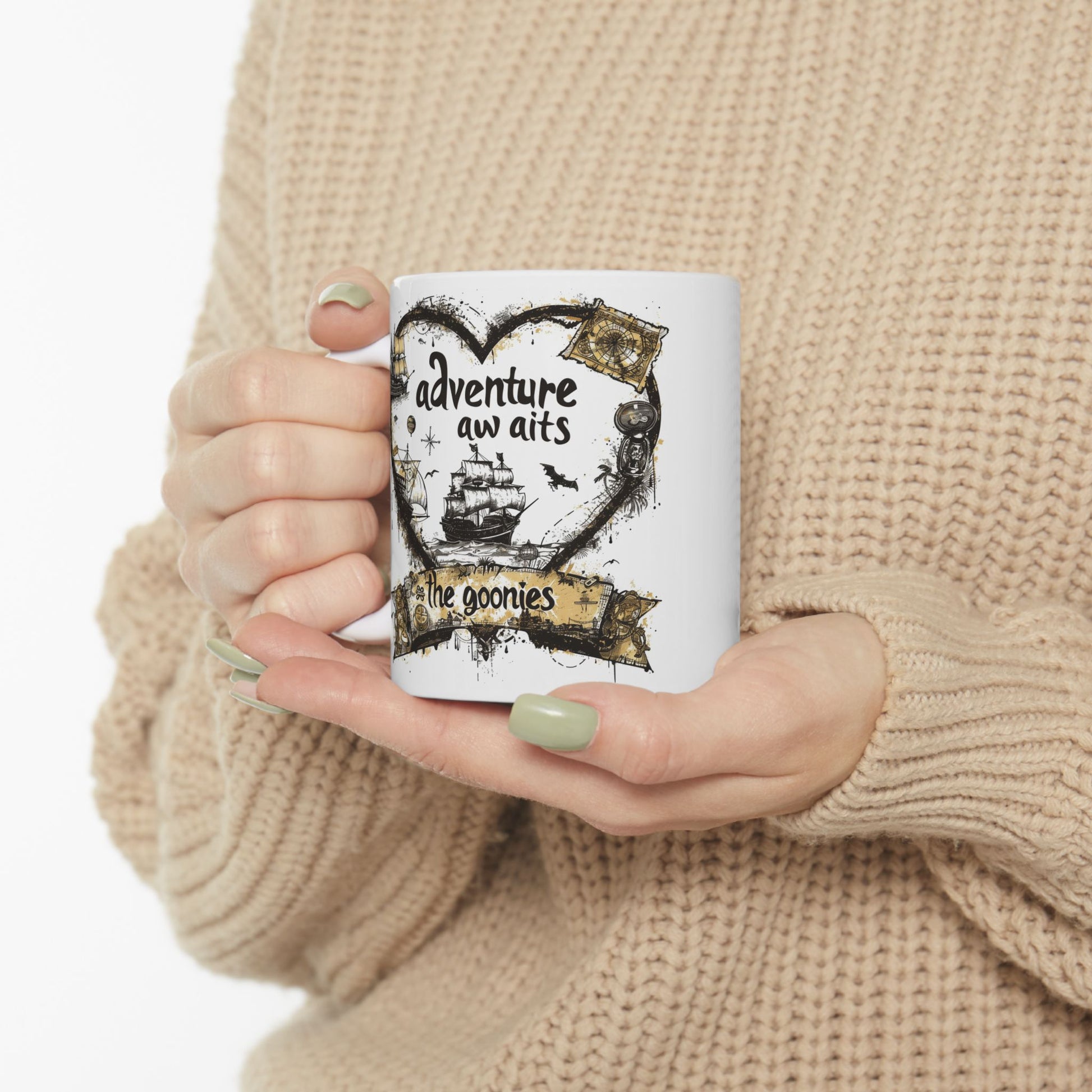 Person holding a mug with 'adventure awaits' design, wearing a beige sweater.