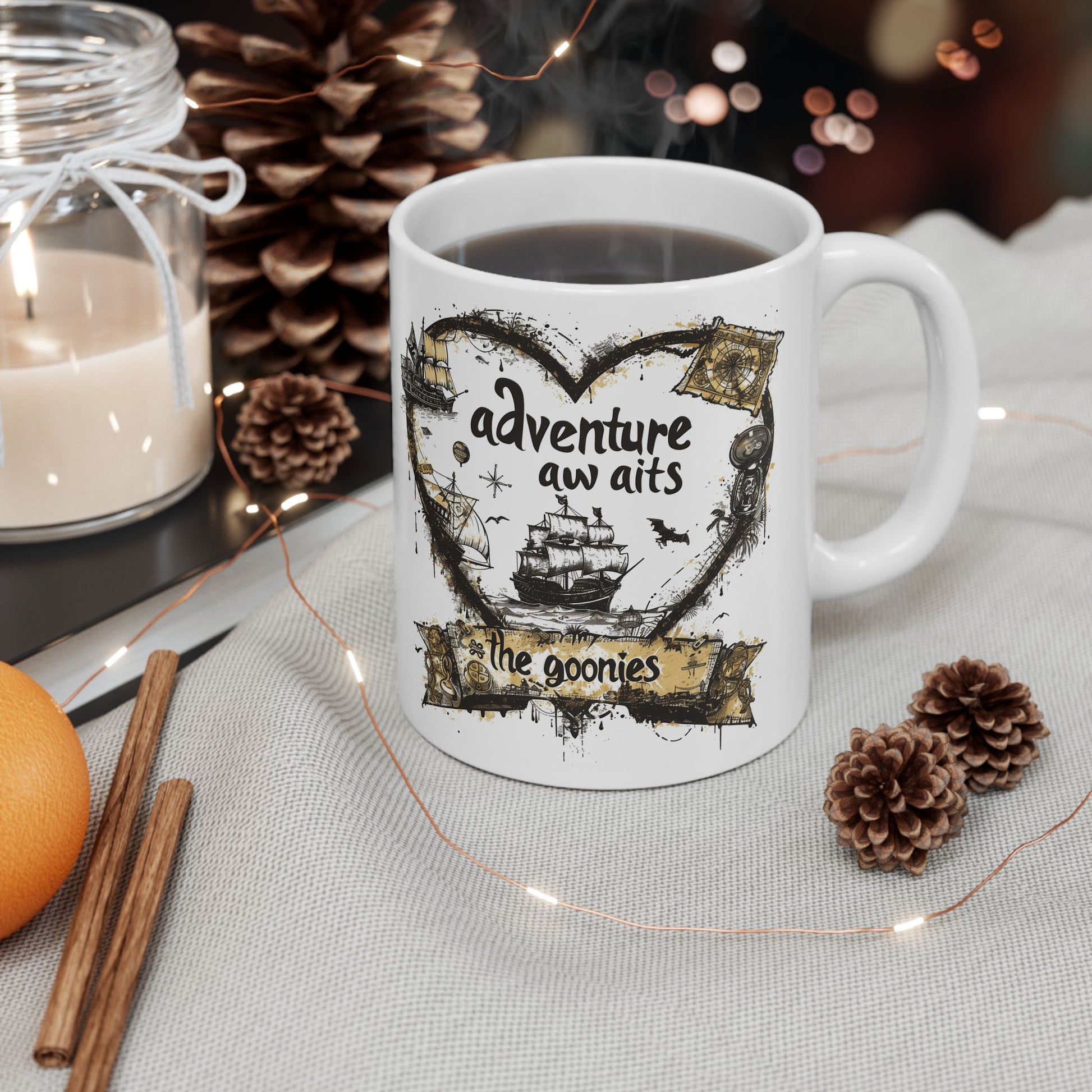 White mug with 'adventure awaits' design, surrounded by decorative items on a table.